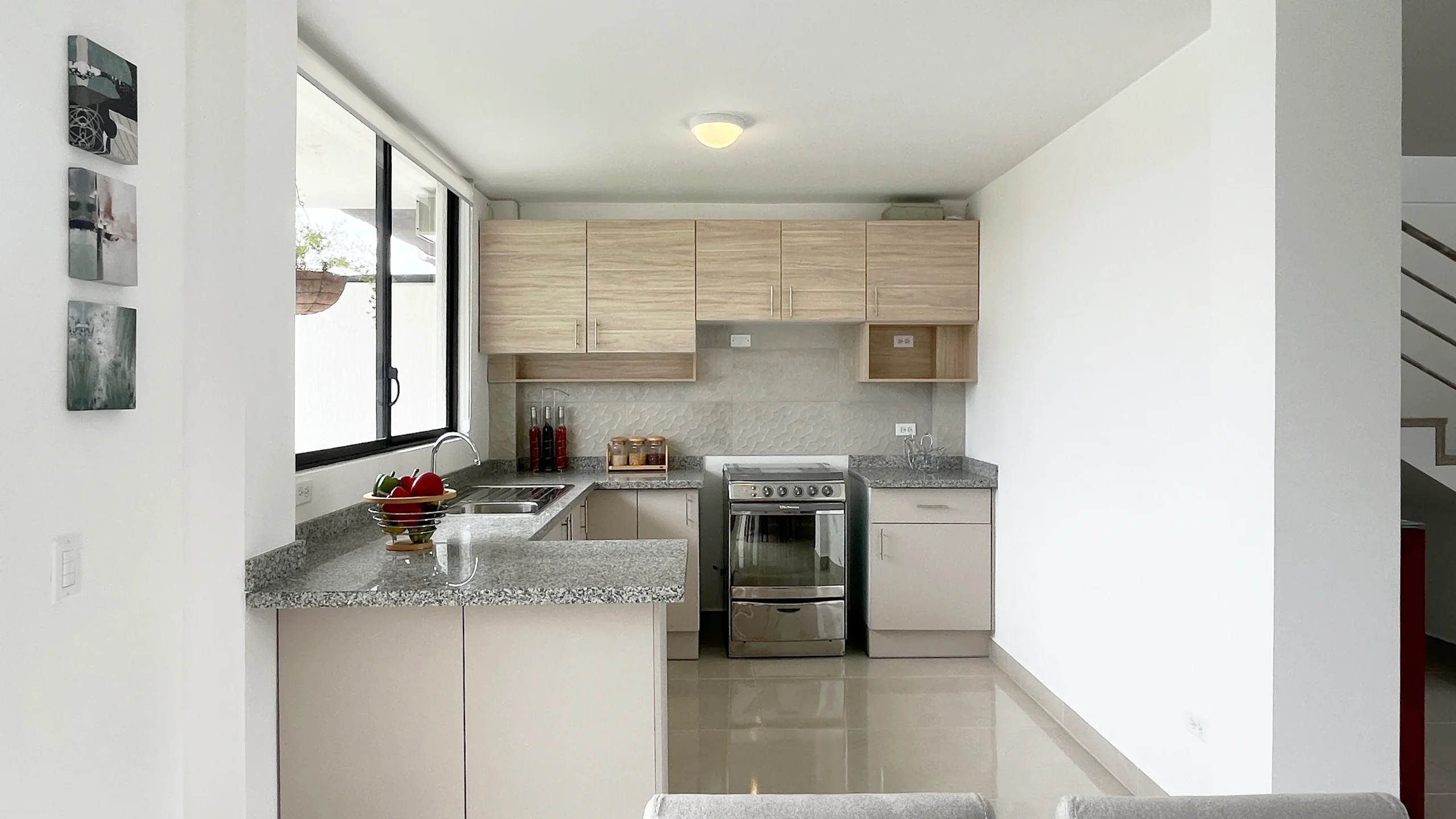 Cocina con muebles de madera clara, mesón de granito y cocina de acero, El Dean