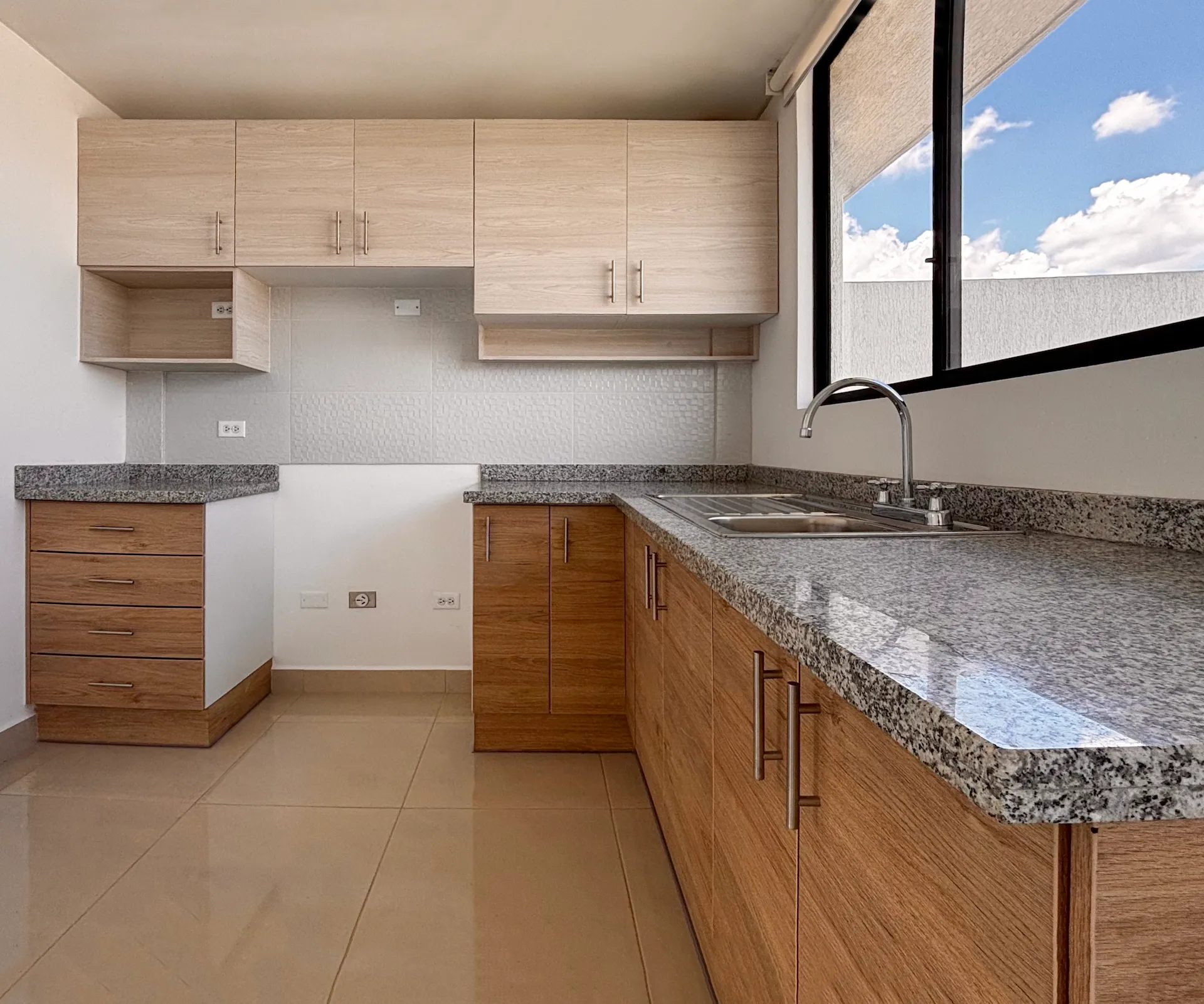 Cocina con muebles de madera clara, mesón de granito y ventana, Santa Lucía