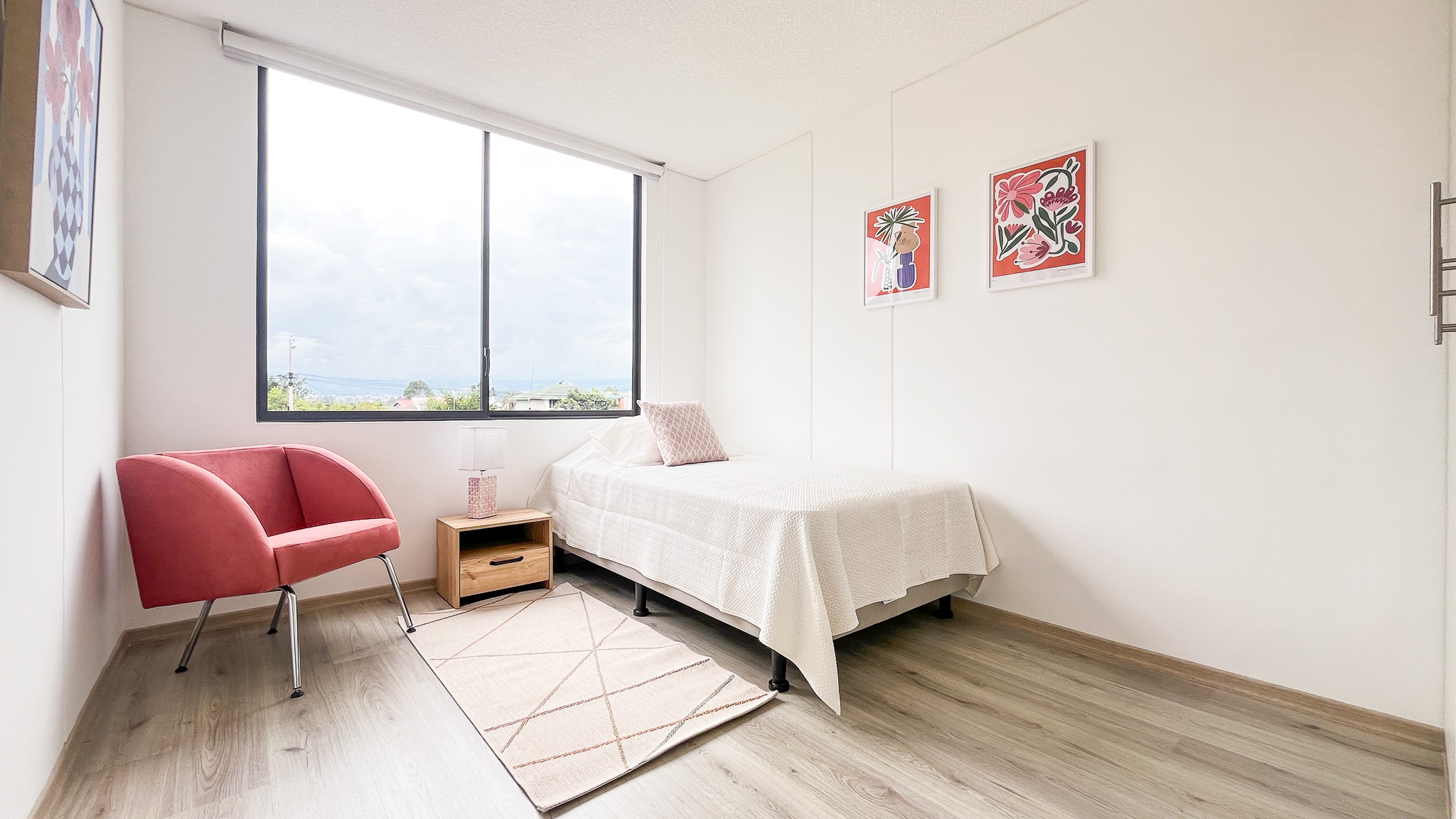 Dormitorio con cama, sillón rosado y ventana amplia, El Dean