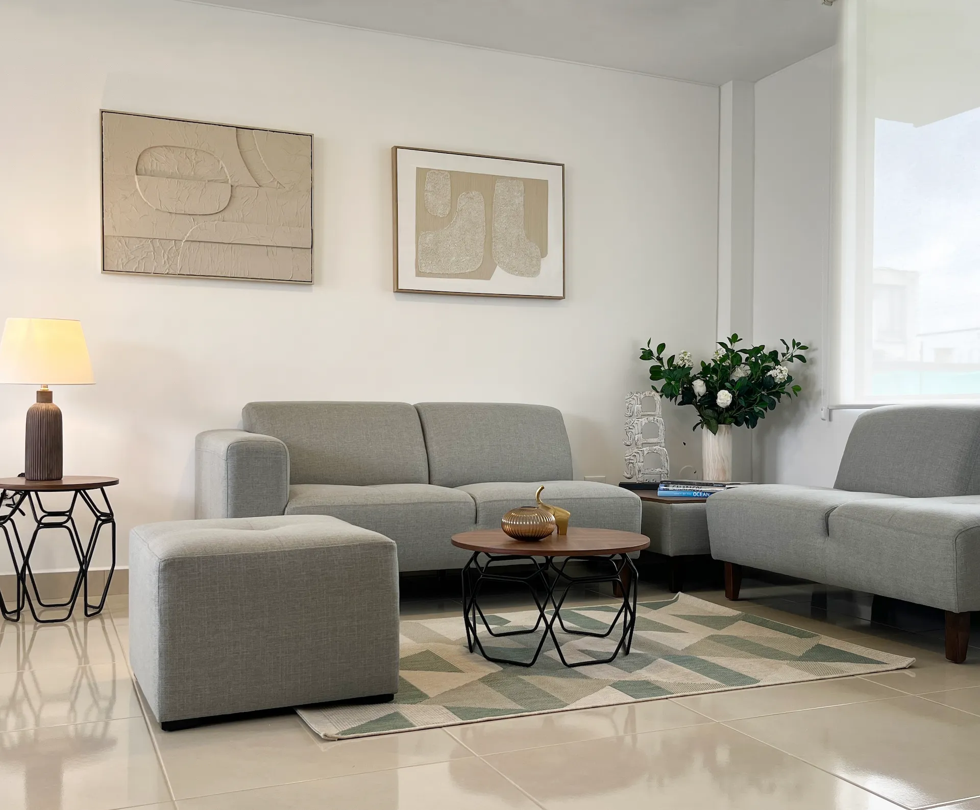 Sala con sofá gris, mesa de centro y cuadros, casa modelo Santa Lucía