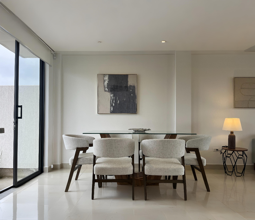 Comedor con mesa de vidrio y cuatro sillas blancas frente a un ventanal, Santa Lucía