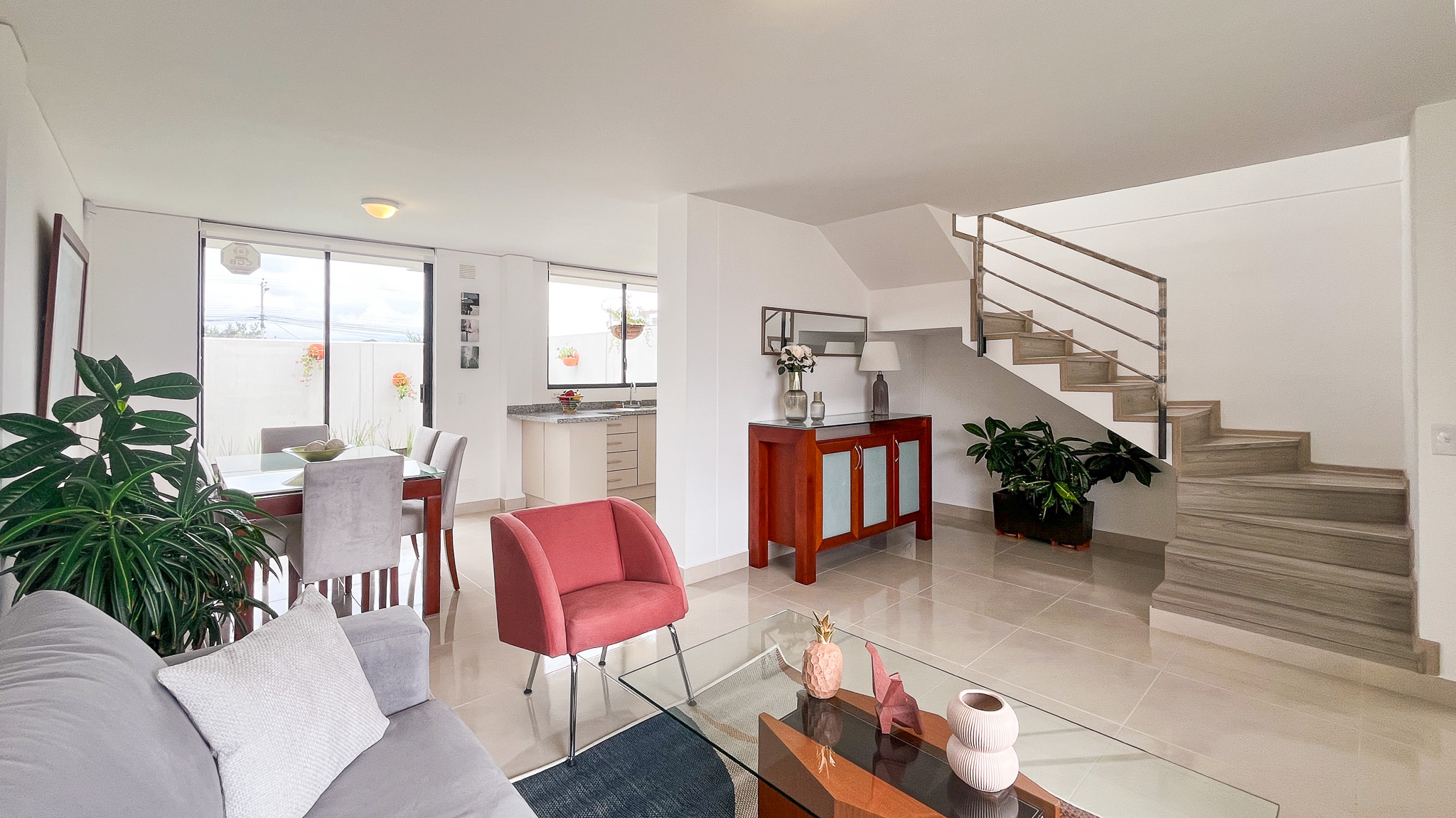 Sala y comedor luminosos con escalera de piso a techo y un sillón rosado, casa modelo El Dean