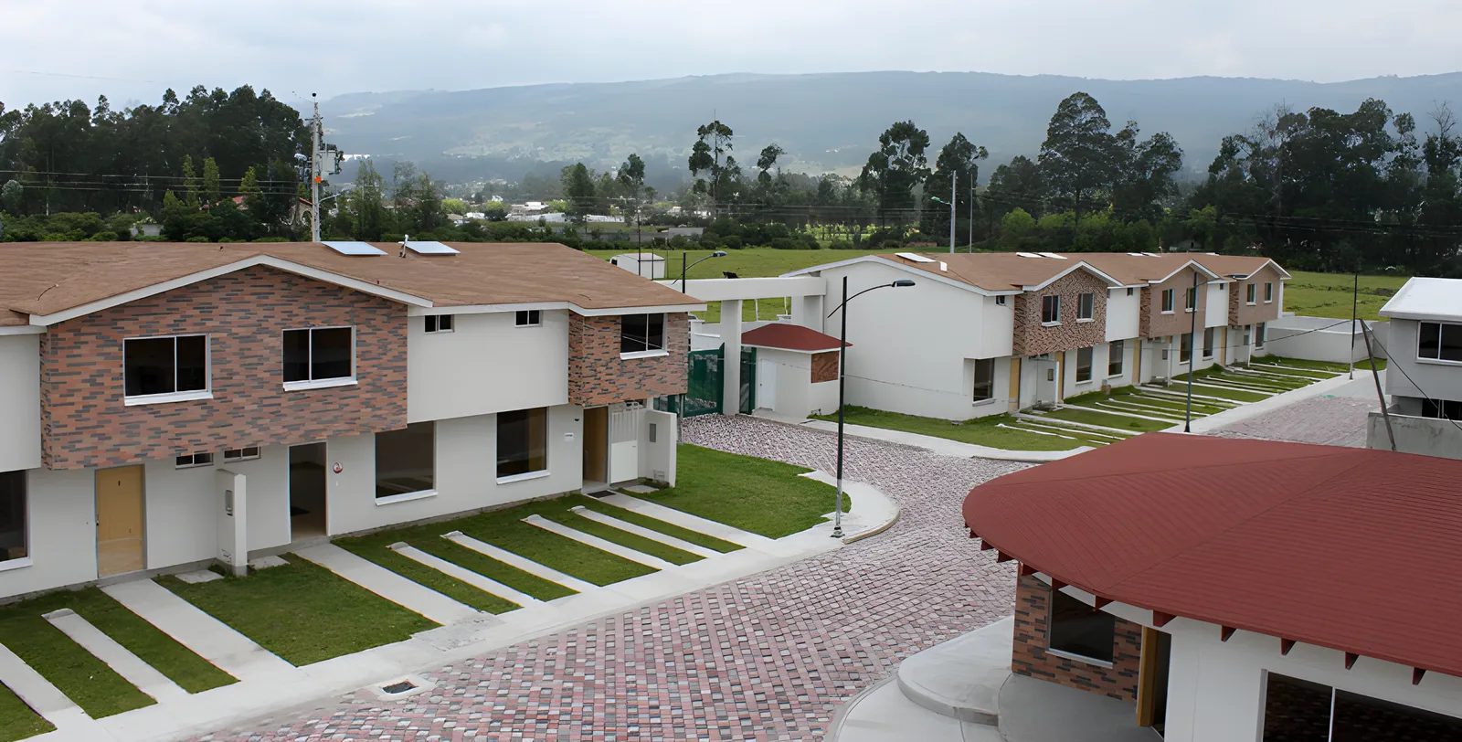 Calle de adoquín rojo con casas de ladrillo y blanco y jardines, Puerta del Sol El Dean