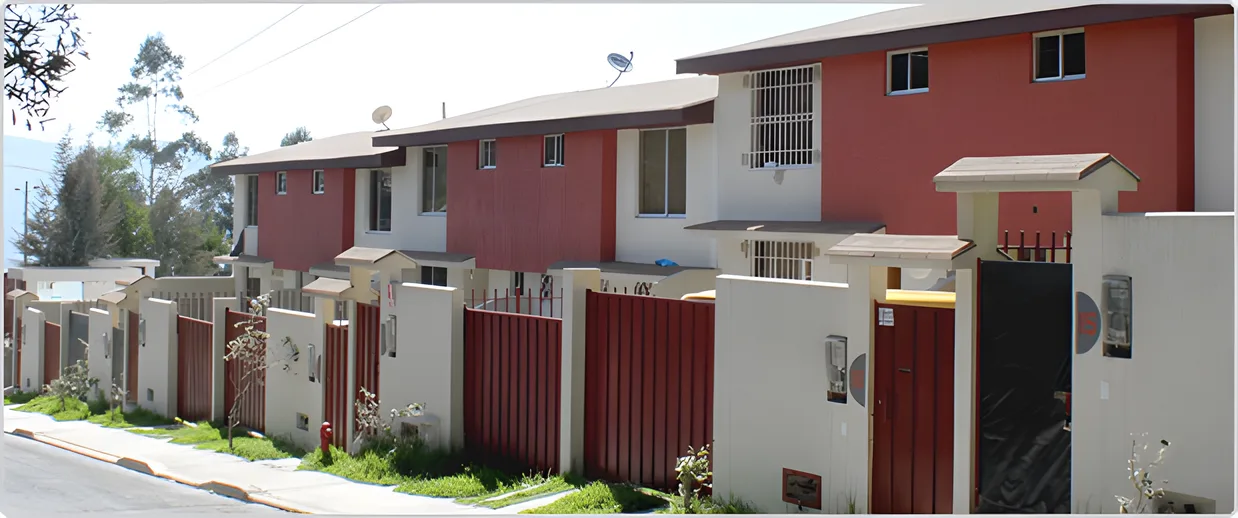 Casas rojas y blancas con portones de madera en una calle con acera, Paseo del Sol 1