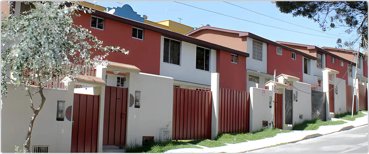 Casas rojas con portones de metal y un árbol florecido, Paseo del Sol 1