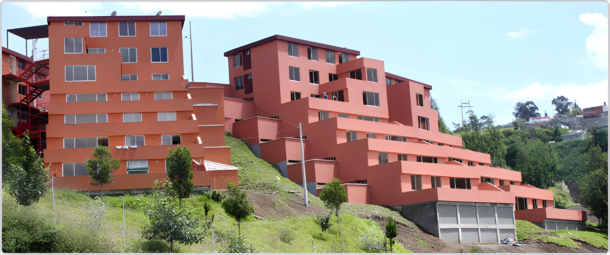 Edificios rojos escalonados en una ladera con árboles, Puerta del Sol Las Acacias
