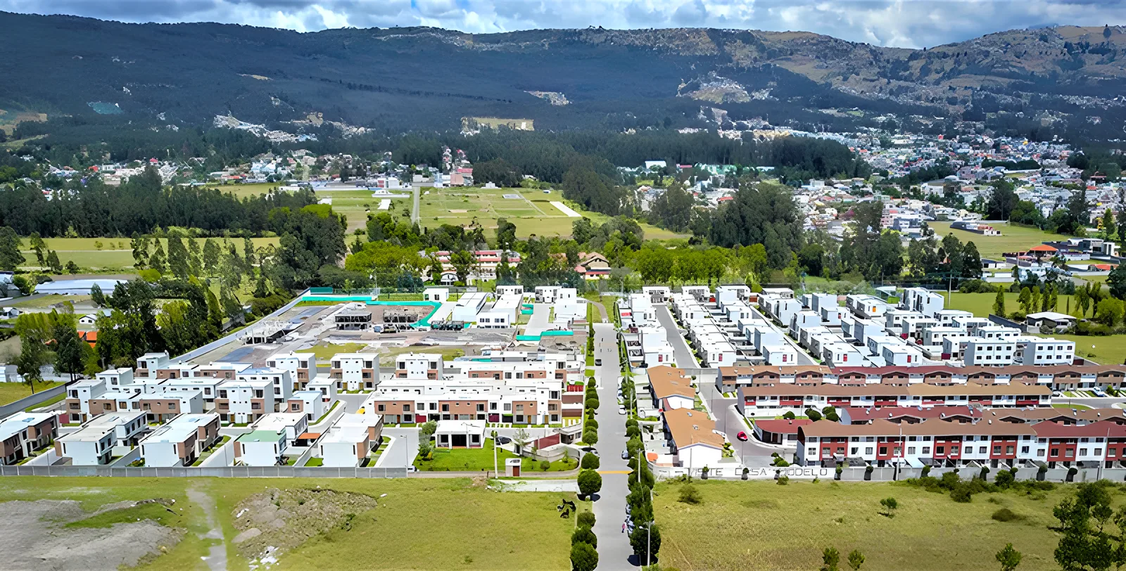 Vista aérea del conjunto de casas blancas y rojas con el valle y las montañas al fondo, Jardines del Dean 2