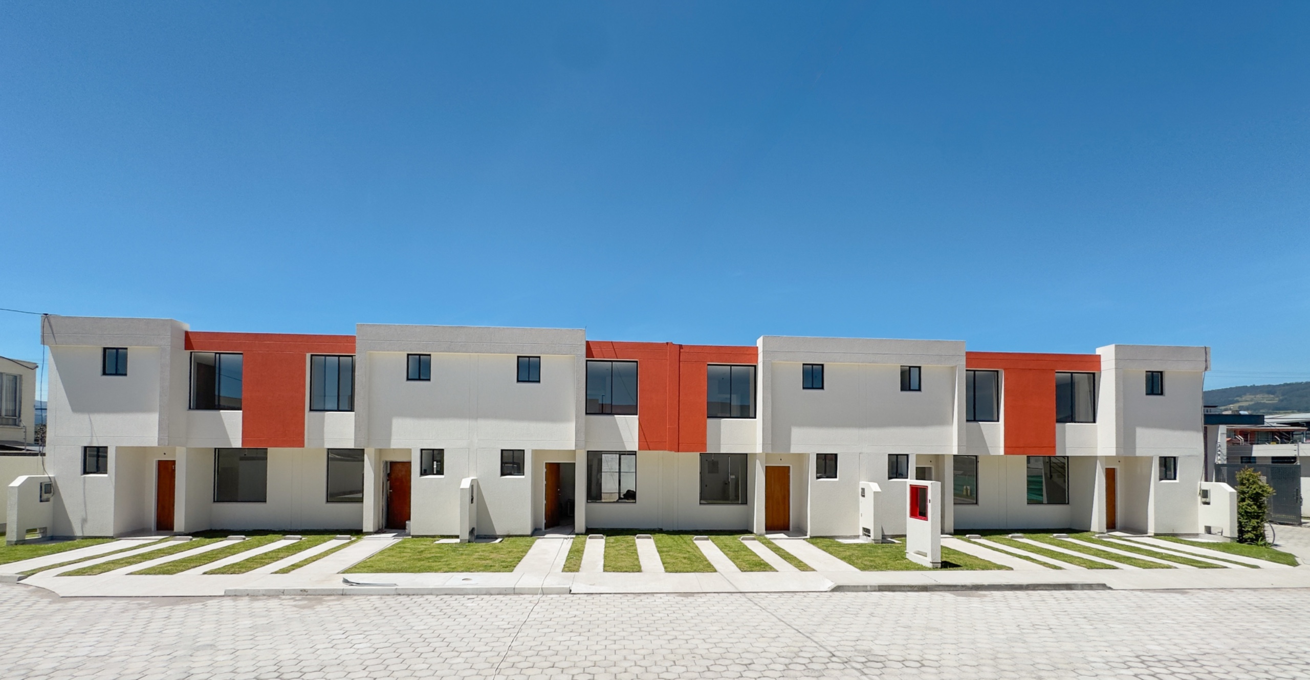 Fila de casas blancas con paneles teja bajo cielo azul despejado, Santa Lucía