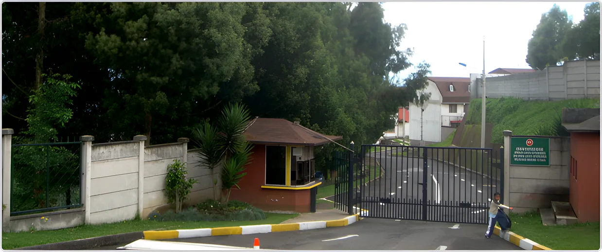 Garita de entrada y portón del conjunto entre árboles, Ciudad Jardín 1