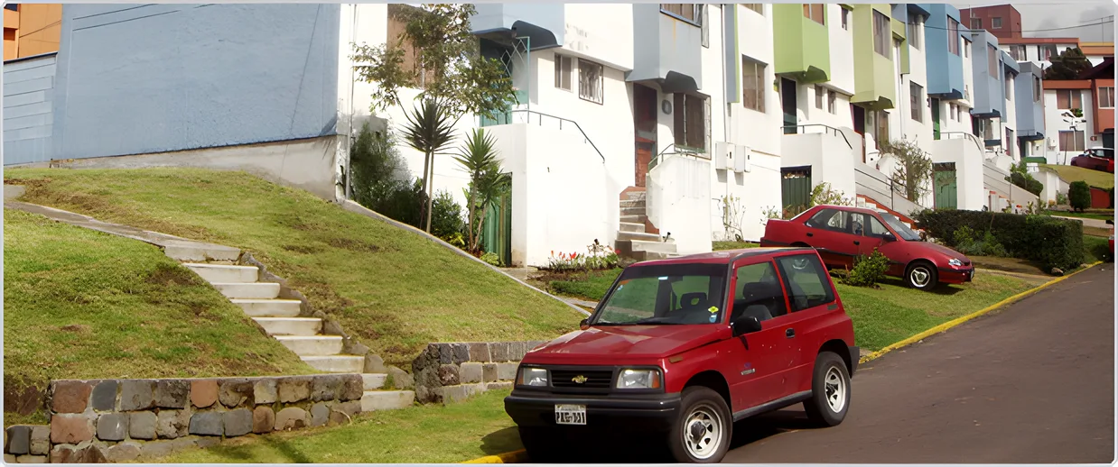 Casas blancas y de colores en una pendiente con un jeep rojo y escalera de piedra, Puerta del Sol II