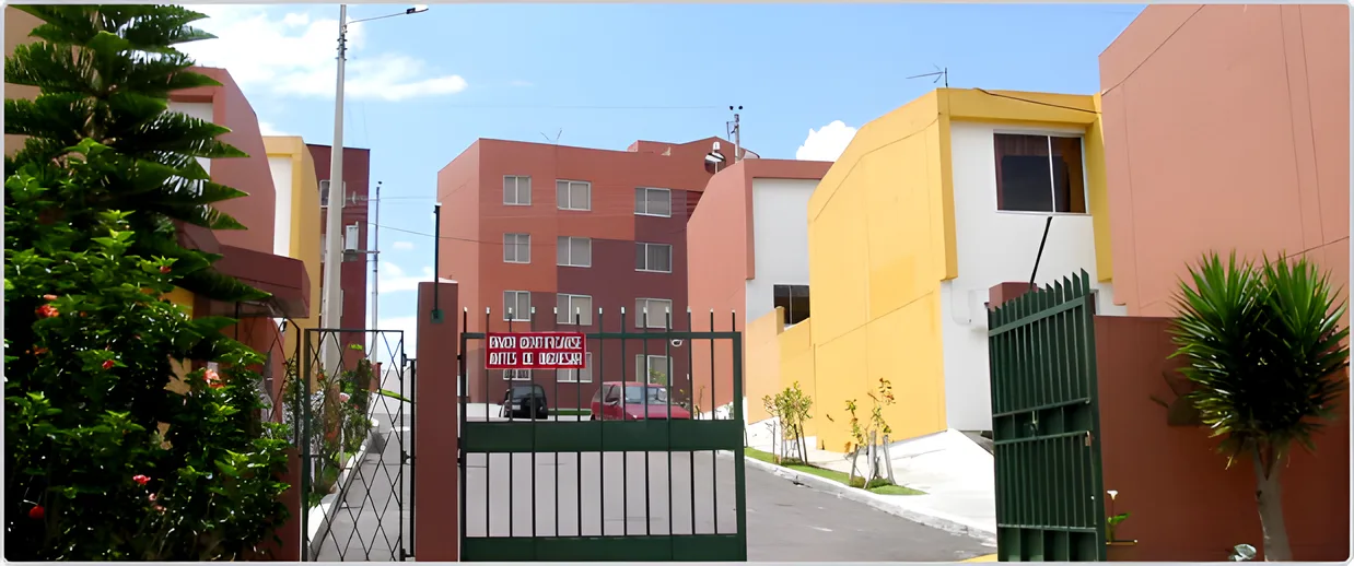 Portón verde de entrada y casas rojas y amarillas con un pino al costado, Puerta del Sol I