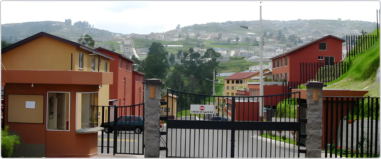 Garita y reja de entrada con casas teja en la ladera, Terrazas del Sol