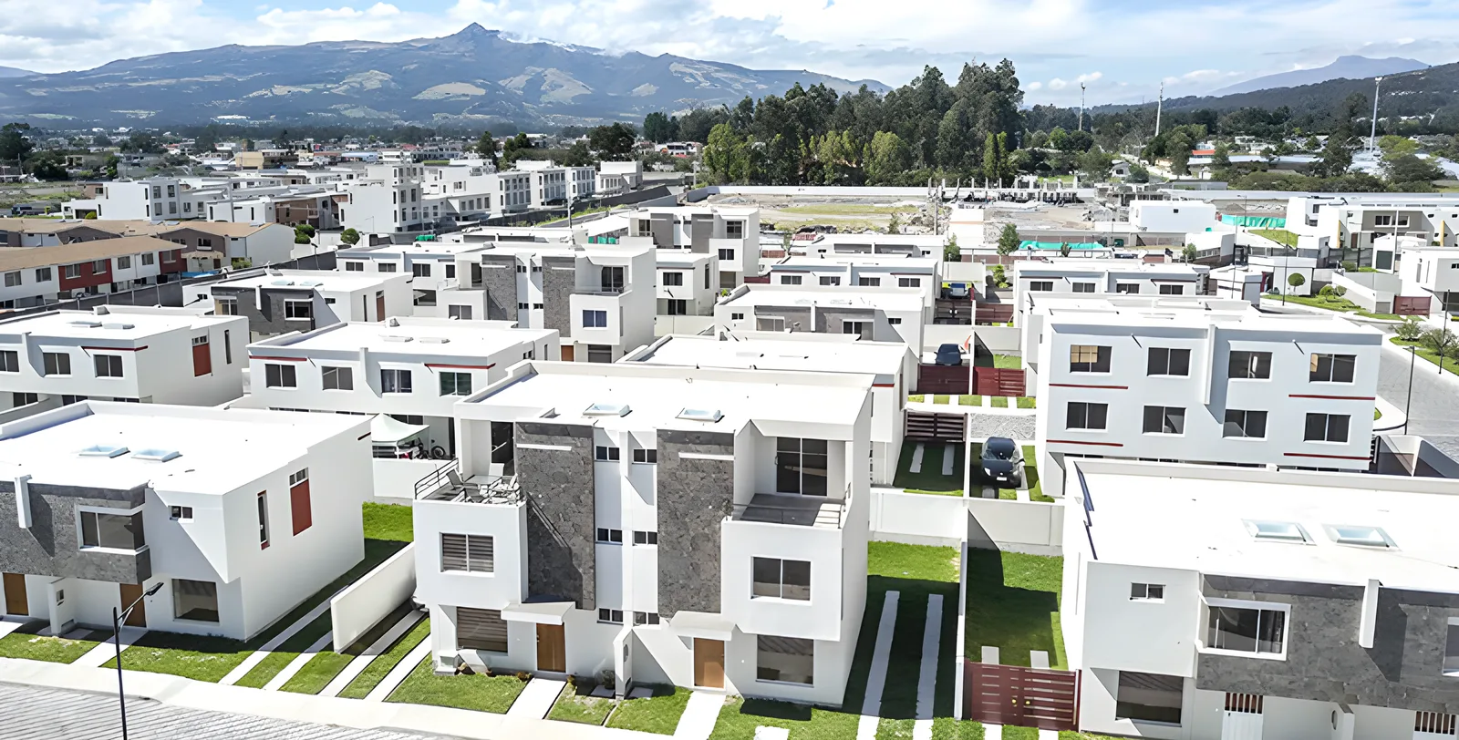 Vista aérea de casas blancas del conjunto con las montañas y el valle al fondo, Jardines del Dean